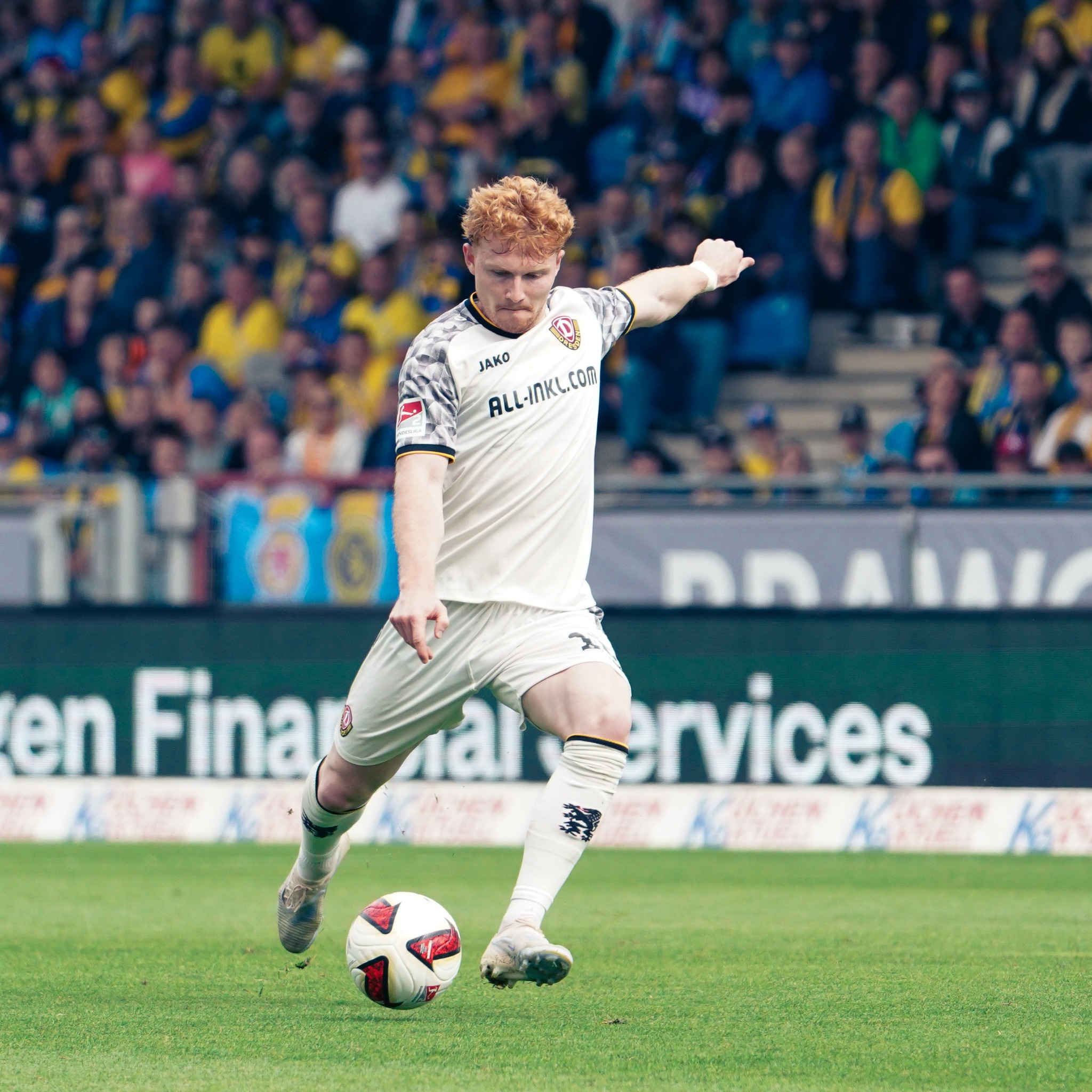 A Dynamo Dresden player controls possession against Eintracht Braunschweig in the 2. Bundesliga.