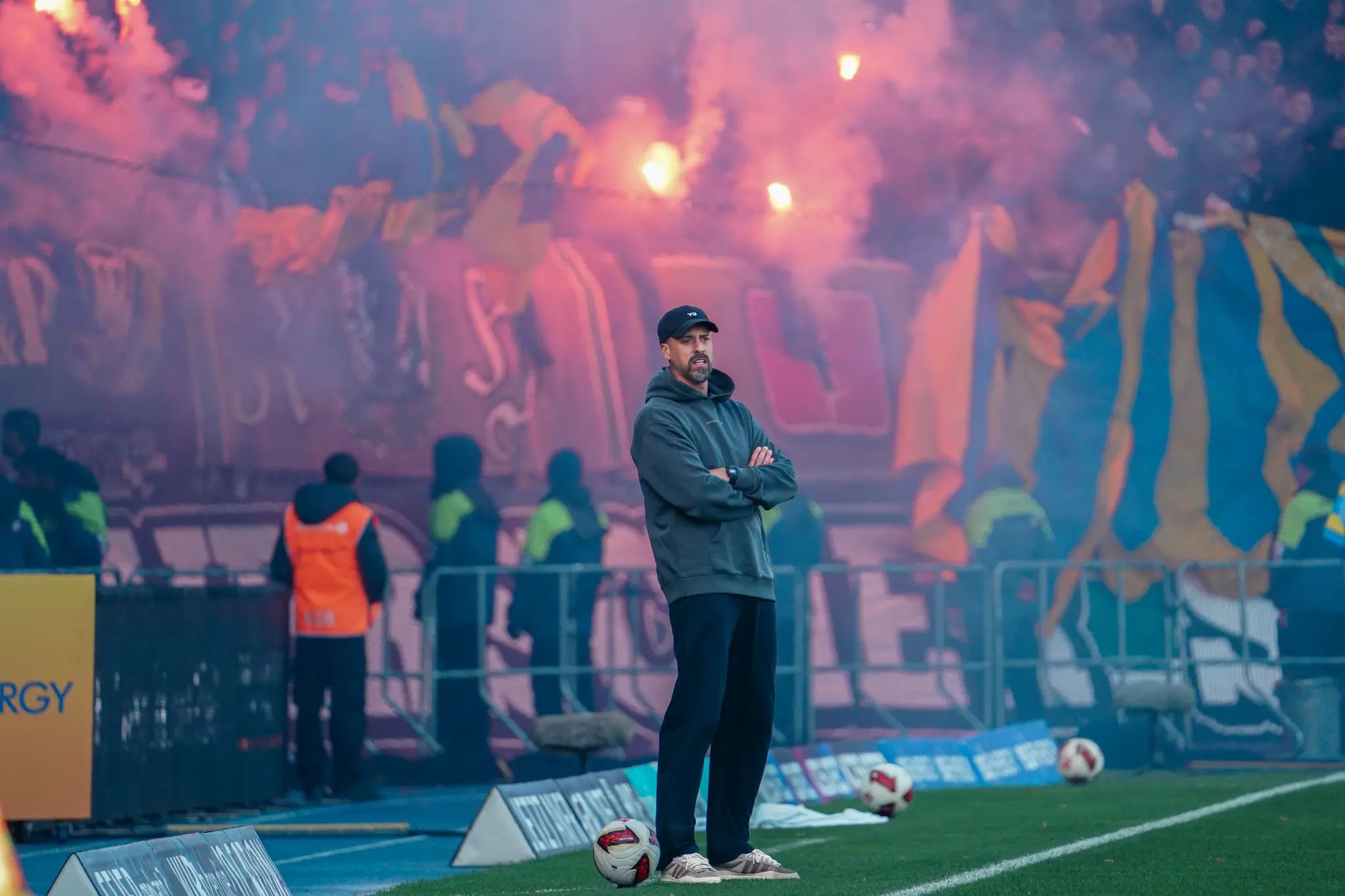 The Hannover 96 coach stands on the touchline amid smoke from the stands.