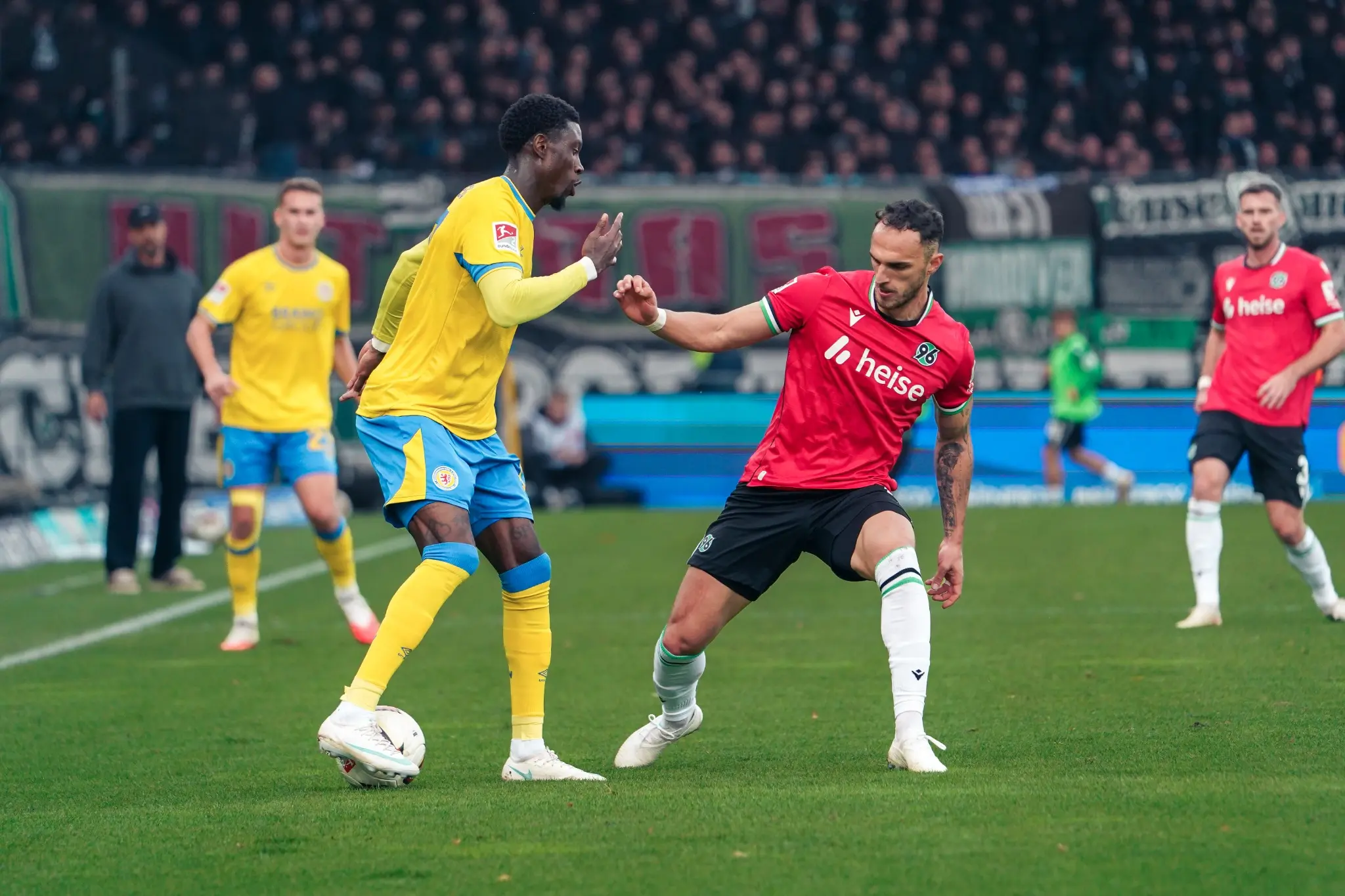 An Eintracht Braunschweig player shields the ball from a Hannover opponent.