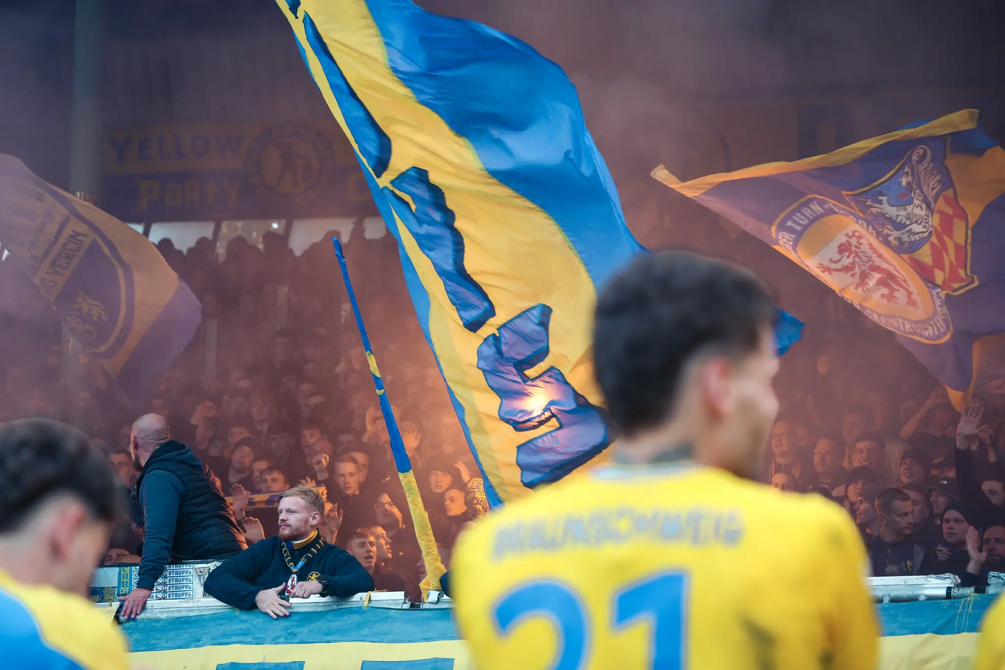 Large blue-and-yellow flags fill the Braunschweig home end.