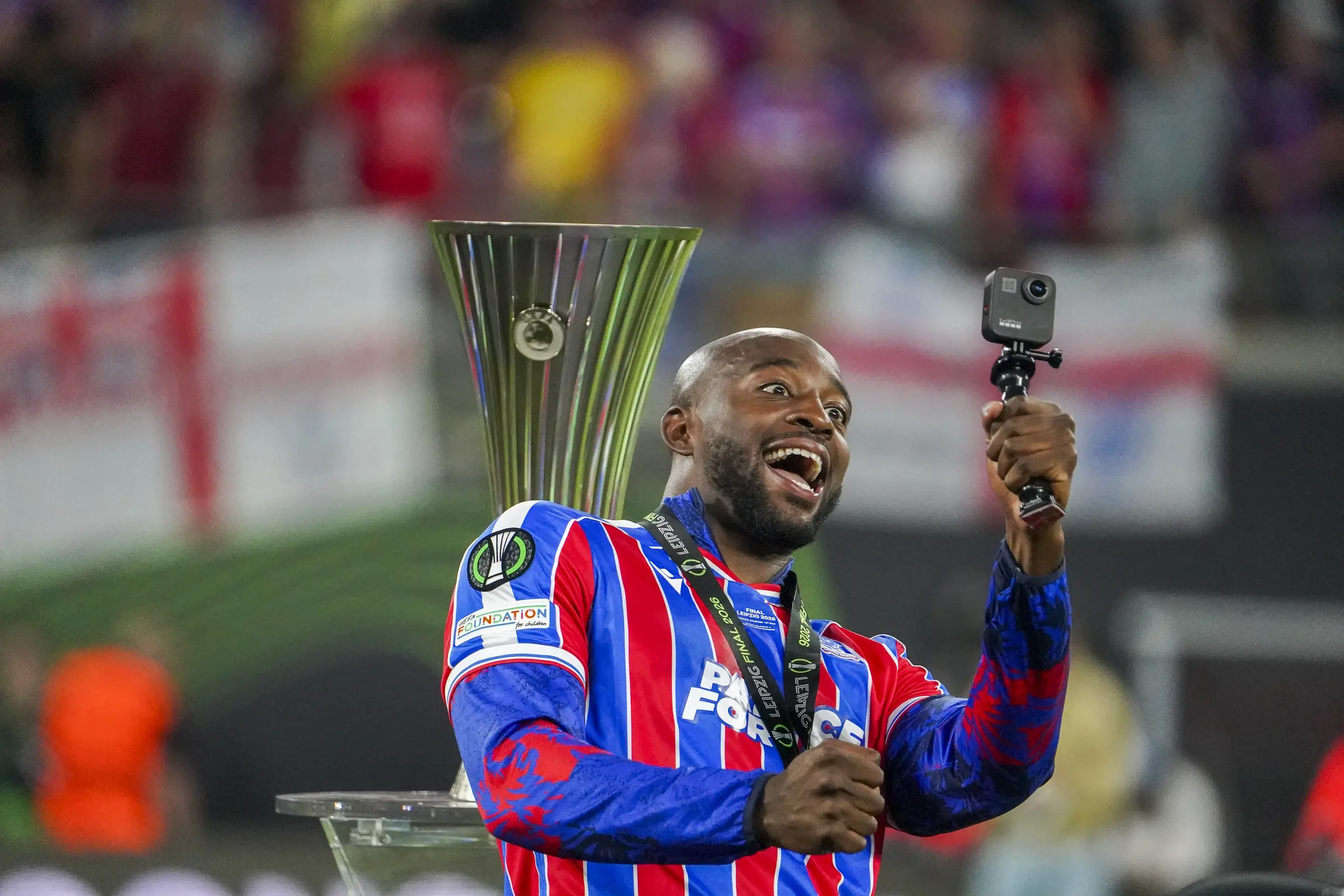 A Crystal Palace player records the celebrations beside the European trophy.