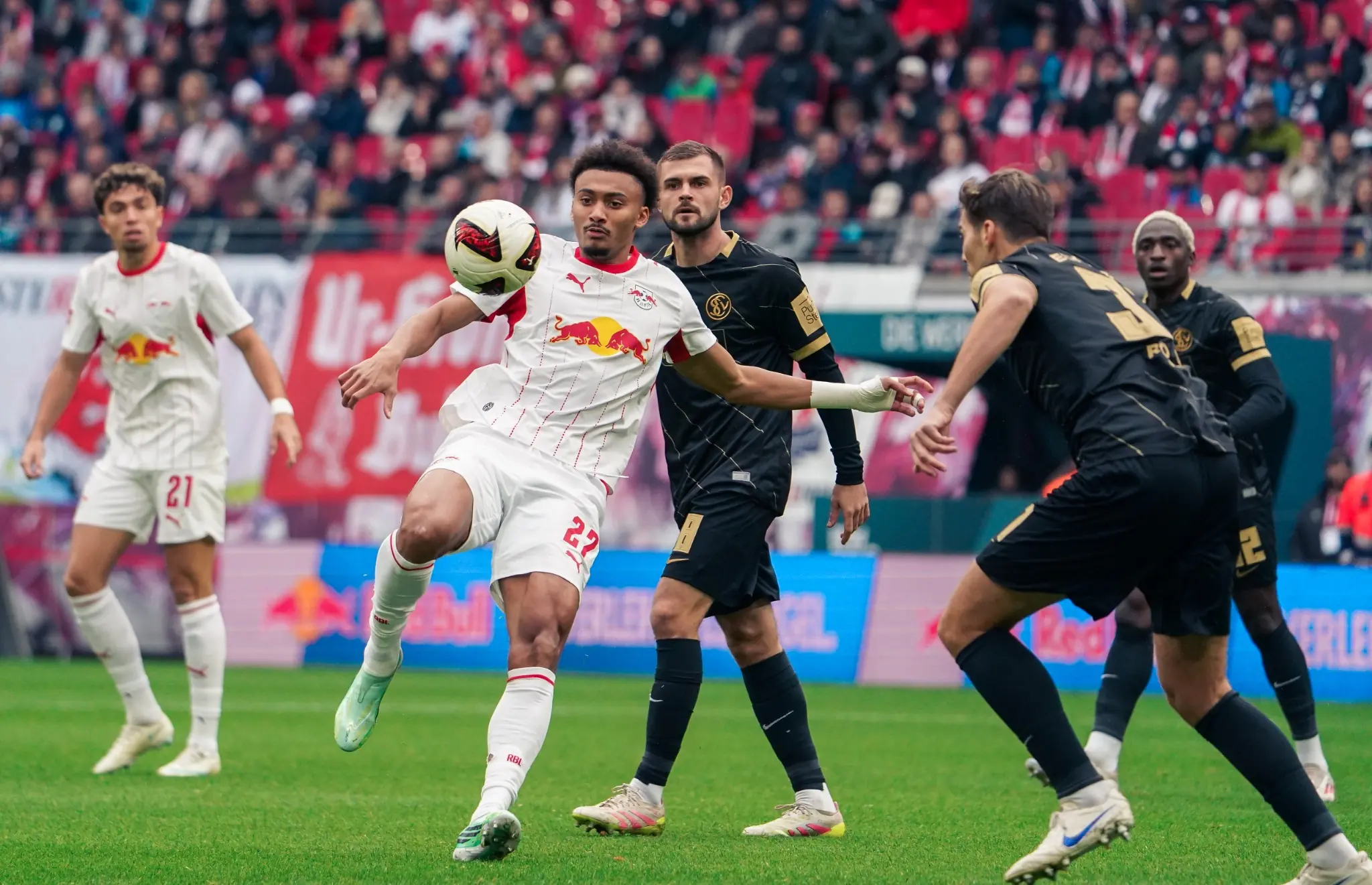 Tidiam Gomis controls the ball under pressure from SV Elversberg defenders in Leipzig.
