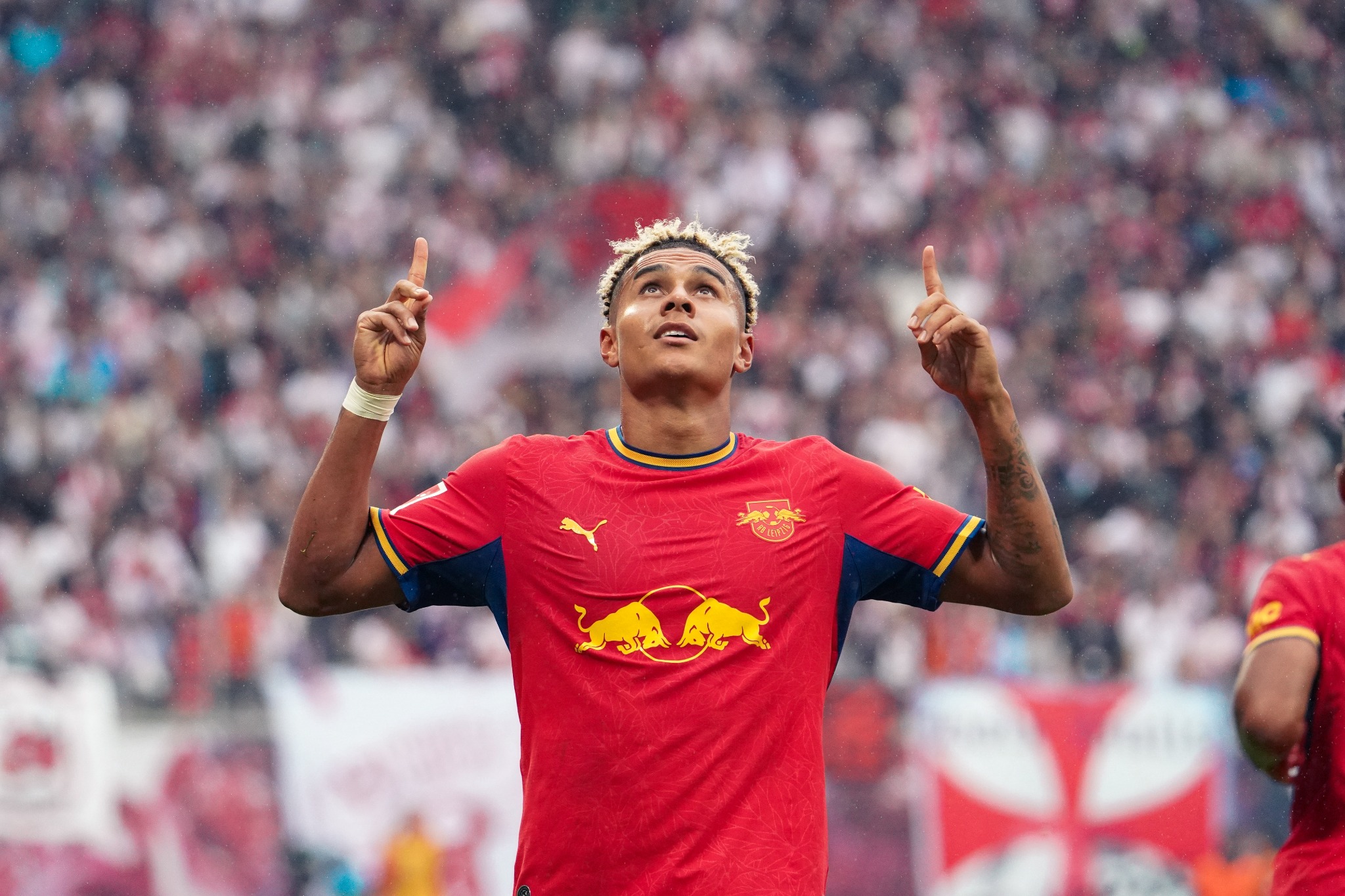 An RB Leipzig player points upward while celebrating against Hamburger SV at the Red Bull Arena.