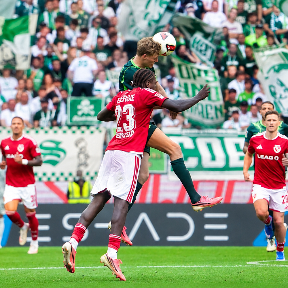 An Energie Cottbus player rises for an aerial ball against VfL Wolfsburg at the Volkswagen Arena.