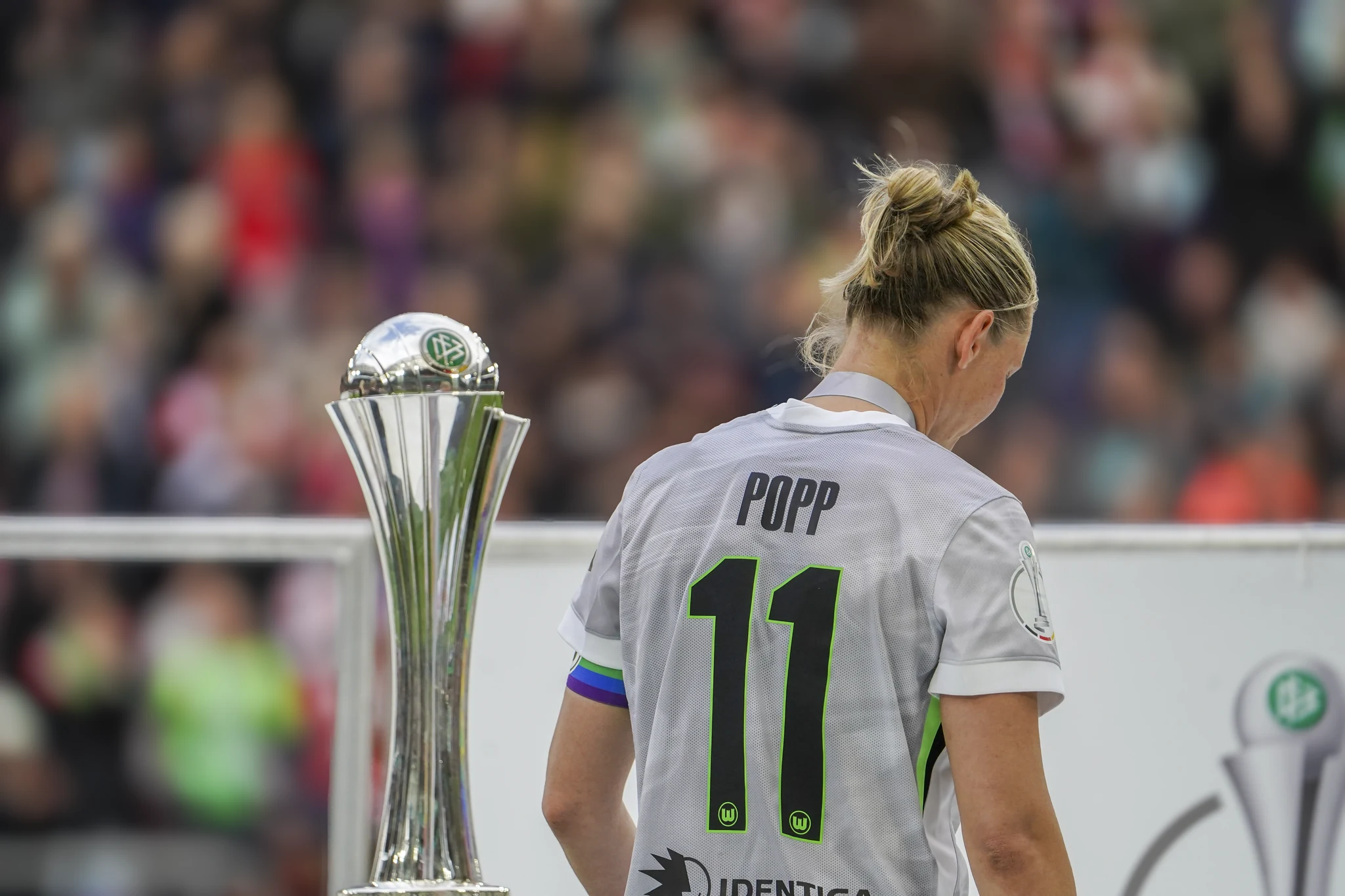 Wolfsburg captain Alexandra Popp walks past the trophy.