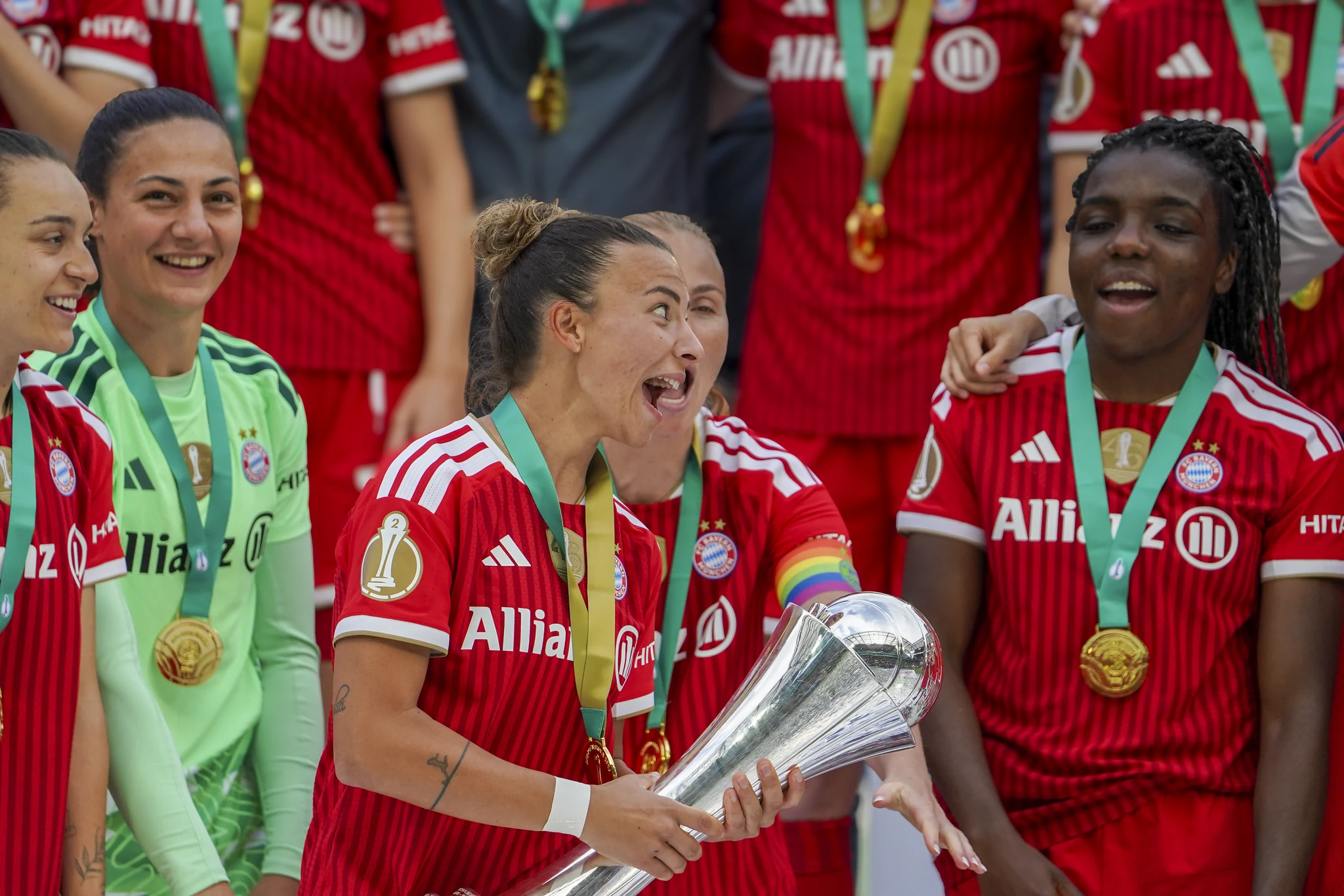 Bayern Munich players smile together around the trophy.